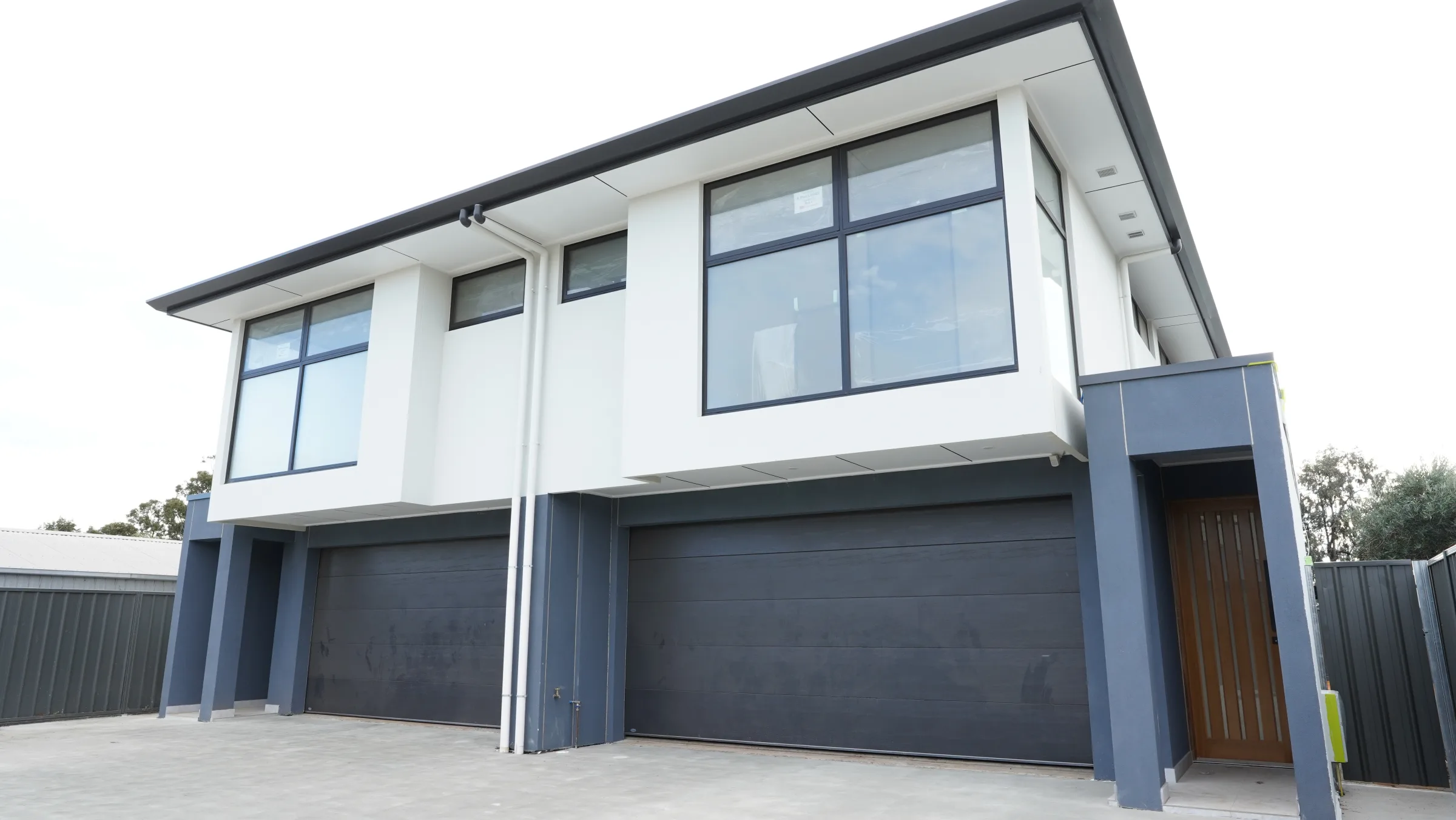 Stone entry residence with dark framed upper windows and double garage frontage
