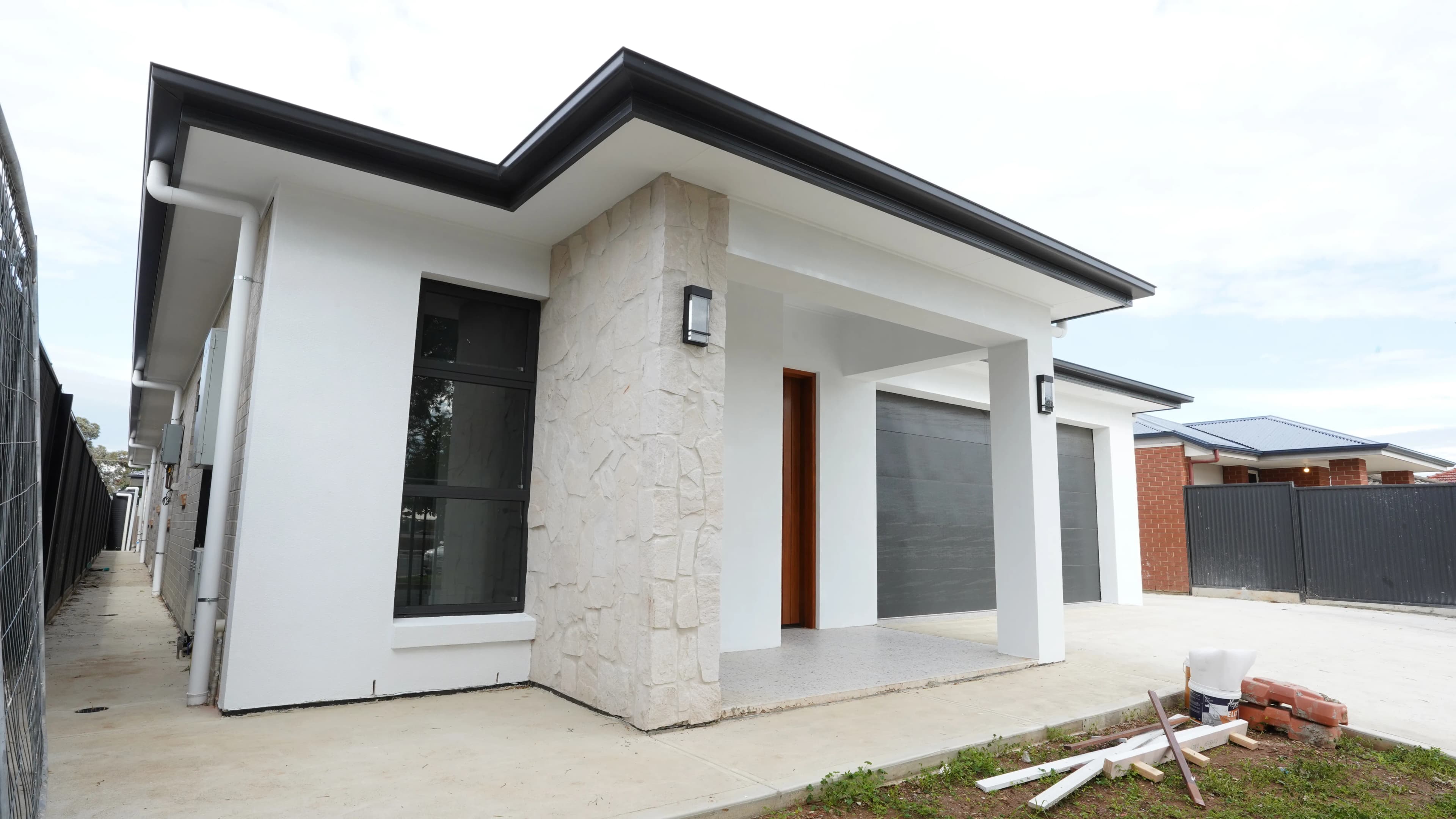 Timber entry residence with stone entry feature, black framed window, timber entry door, and garage frontage