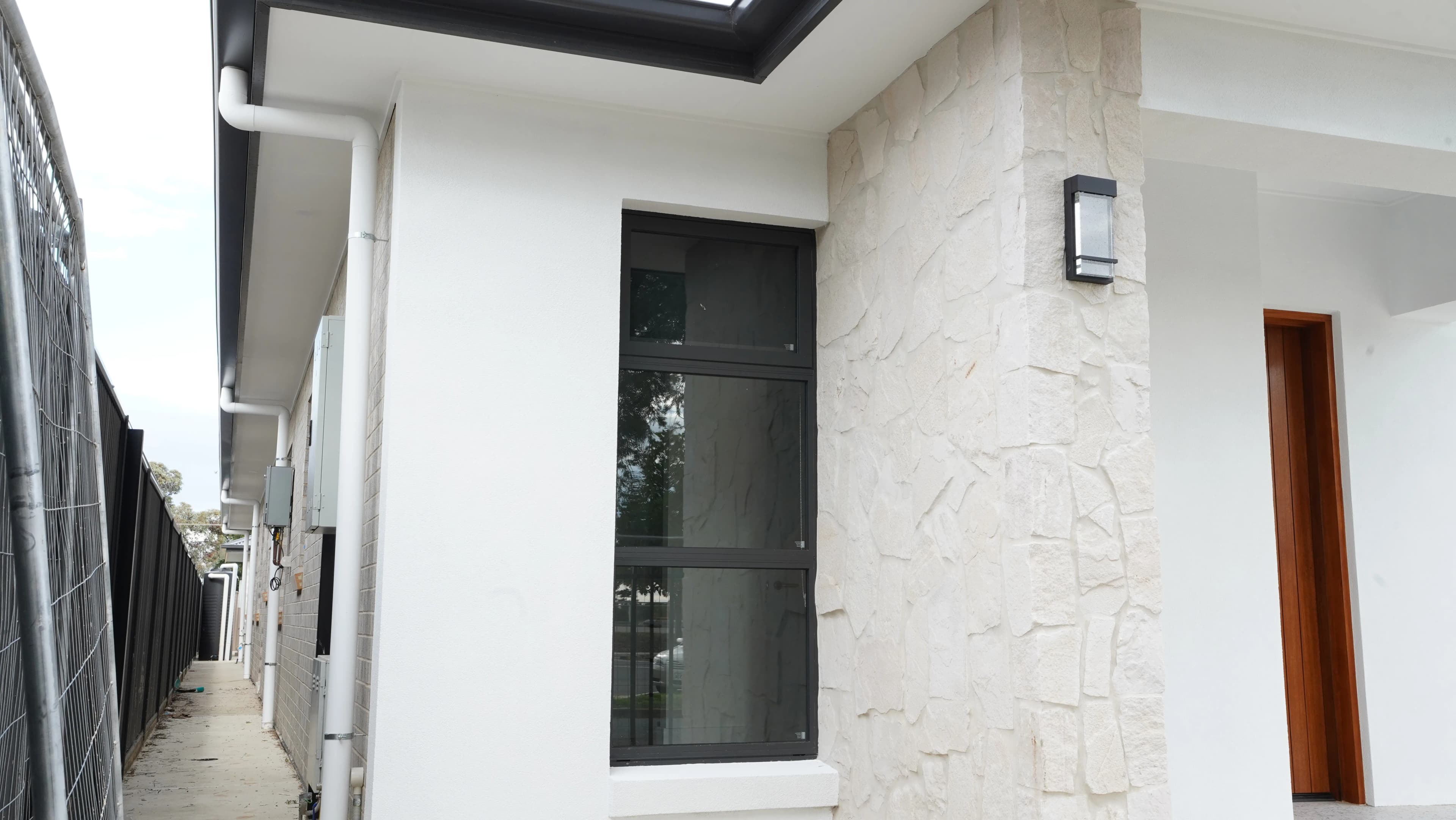 Black framed front window beside stone entry cladding